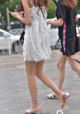 身材苗条的羽毛裙美女，逛街的白色短裙大白腿女孩图片